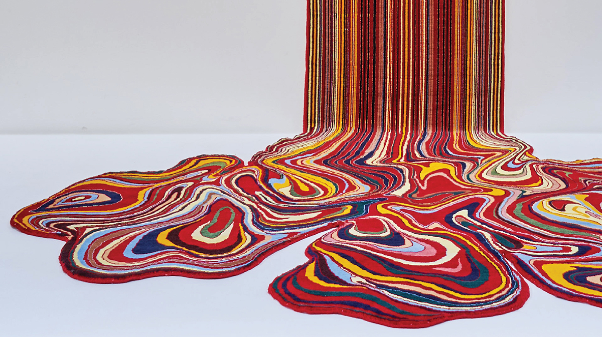 A painting-like sculpture with bright colours, including blue, red, and yellow, appears to ooze down a wall and swirl together on a white floor. 